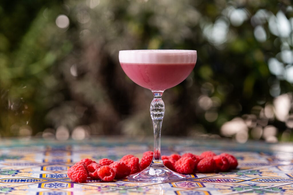 Pink raspberry cocktail on a tiled patio table