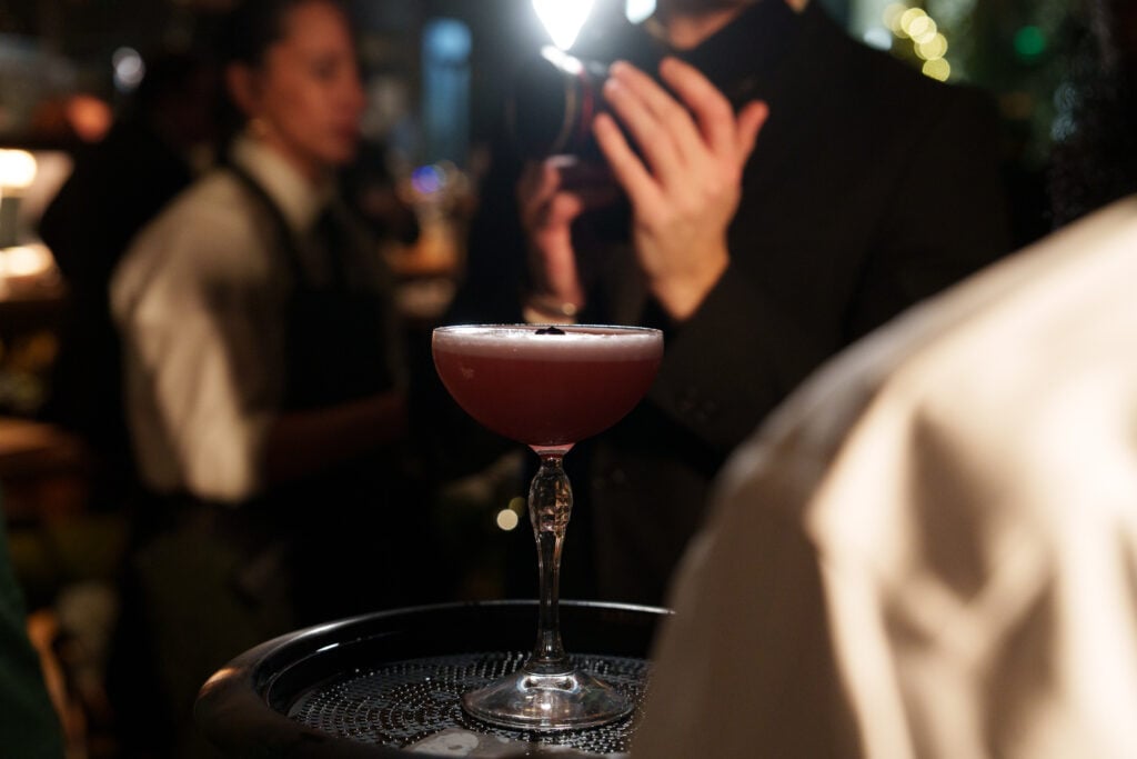 Cocktail on a bar tray with guests in the background