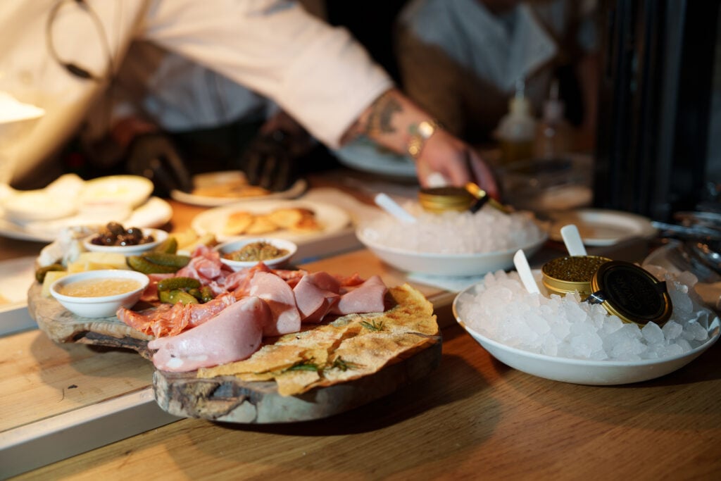Chef plating charcuterie, focaccia and caviar at the open kitchen