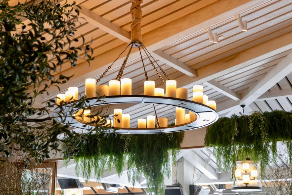 Candle chandelier under the wooden ceiling with hanging greenery