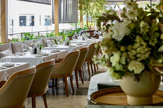 Patio tables with white tablecloths and fresh flowers